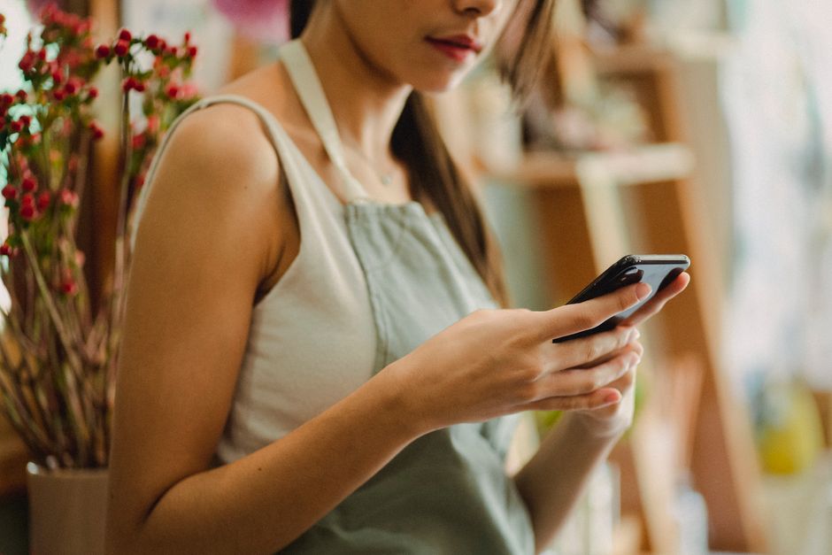 店内でスマートフォンを操作しながら投稿内容を確認する店舗スタッフ