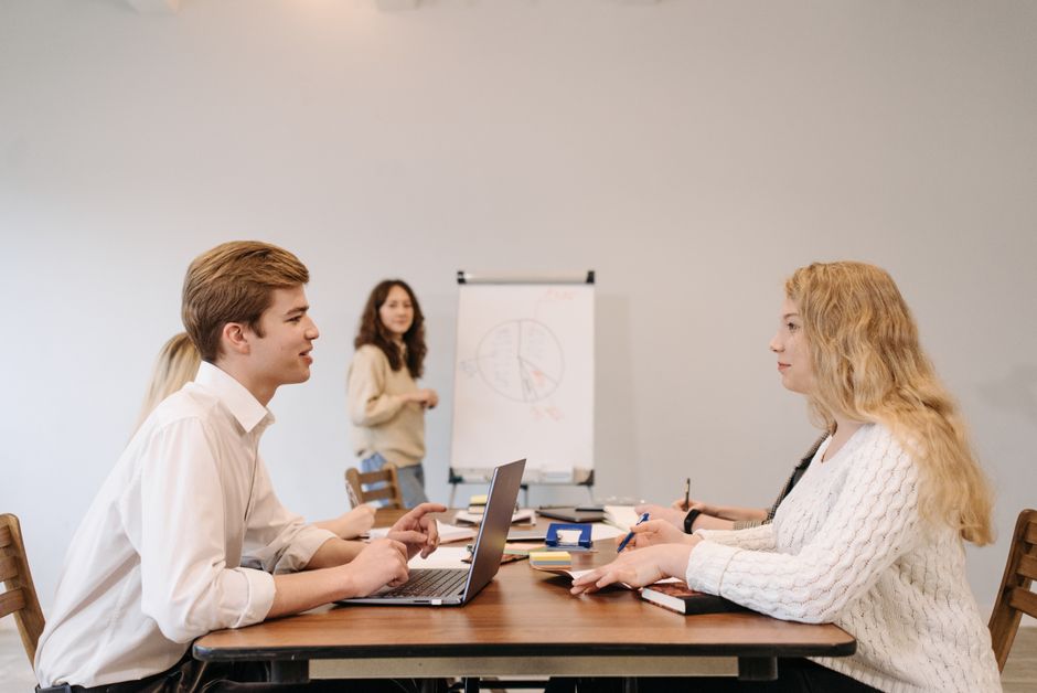 若手社員がオフィスで集まって打ち合わせをしている様子